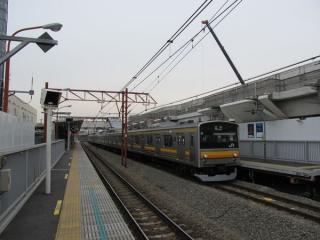 稲城長沼駅2番線に停車中の立川行き205系電車。背後では高架橋の建設が進む。